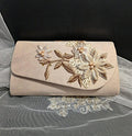 Beige clutch bag with floral embroidery on a black background