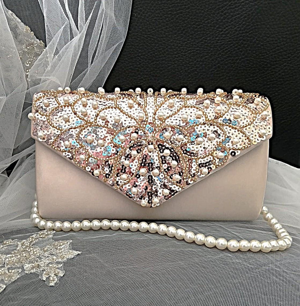 Elegant champagne clutch bag with beaded and sequined top section on a black background