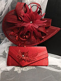 Burgundy hat and matching clutch with floral embellishments on a white lace background