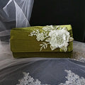 Olive Green clutch bag with floral embroidery on a fabric background