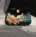 Green clutch with gold floral embellishments on a sheer fabric background