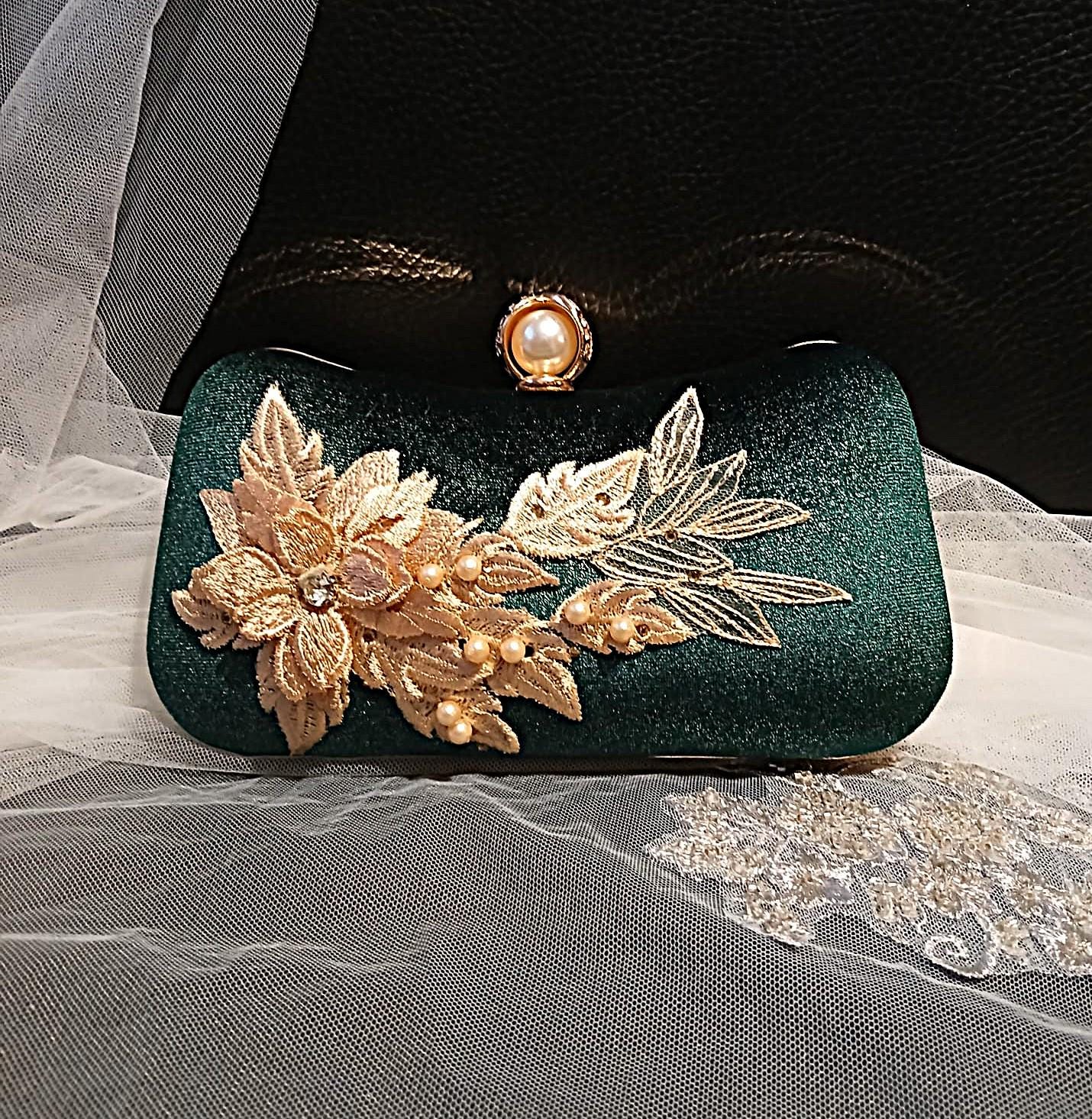 Green clutch with gold floral embellishments on a sheer fabric background
