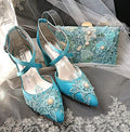 Set of turquoise wedding shoes and clutch with floral lace details on a gray fabric background.