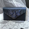 Navy Blue clutch with floral embellishments on a lace fabric background