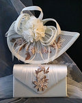 Ivory fascinator with floral details on a matching clutch bag against a dark background