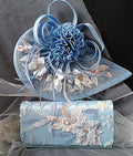 Blue floral embroidered clutch bag and hat on a gray background