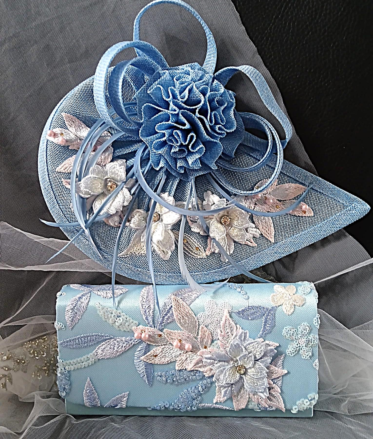 Blue floral embroidered clutch bag and hat on a gray background