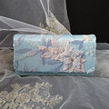 Light blue clutch bag with floral embroidery on a sheer fabric background