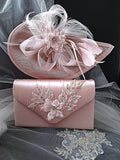 Pink fascinator and clutch bag with floral details on a gray fabric background