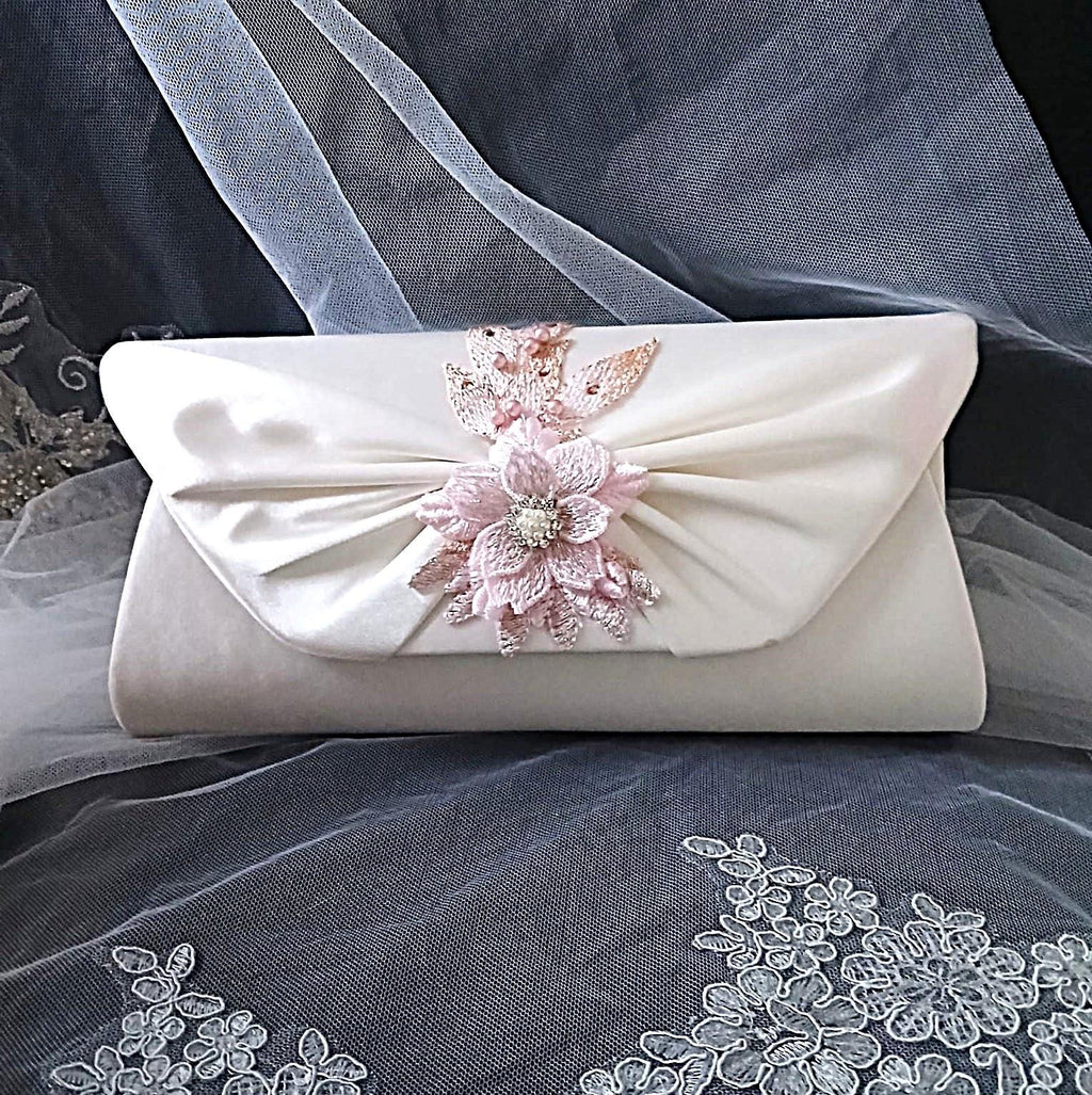 Ivory clutch bag with floral embellishment on a gray fabric background