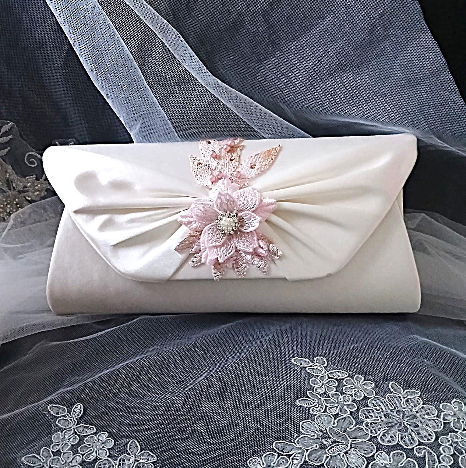 Ivory clutch bag with floral embellishment on a gray fabric background