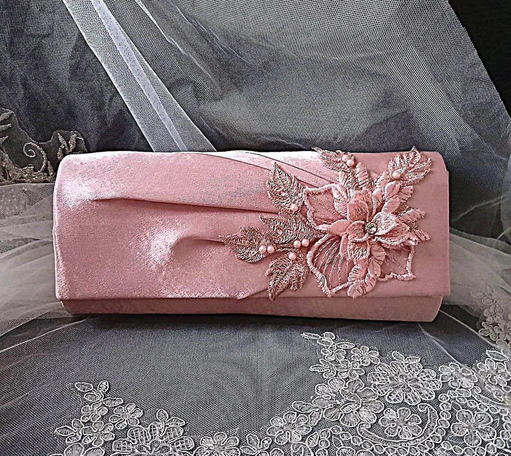 Dusky Pink clutch bag with floral embroidery on a gray fabric background
