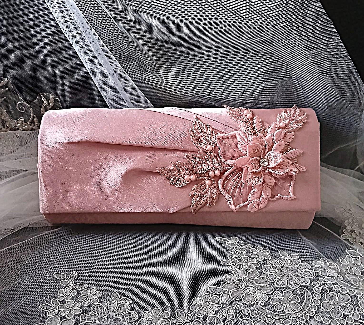 Dusky Pink clutch bag with floral embroidery on a gray fabric background