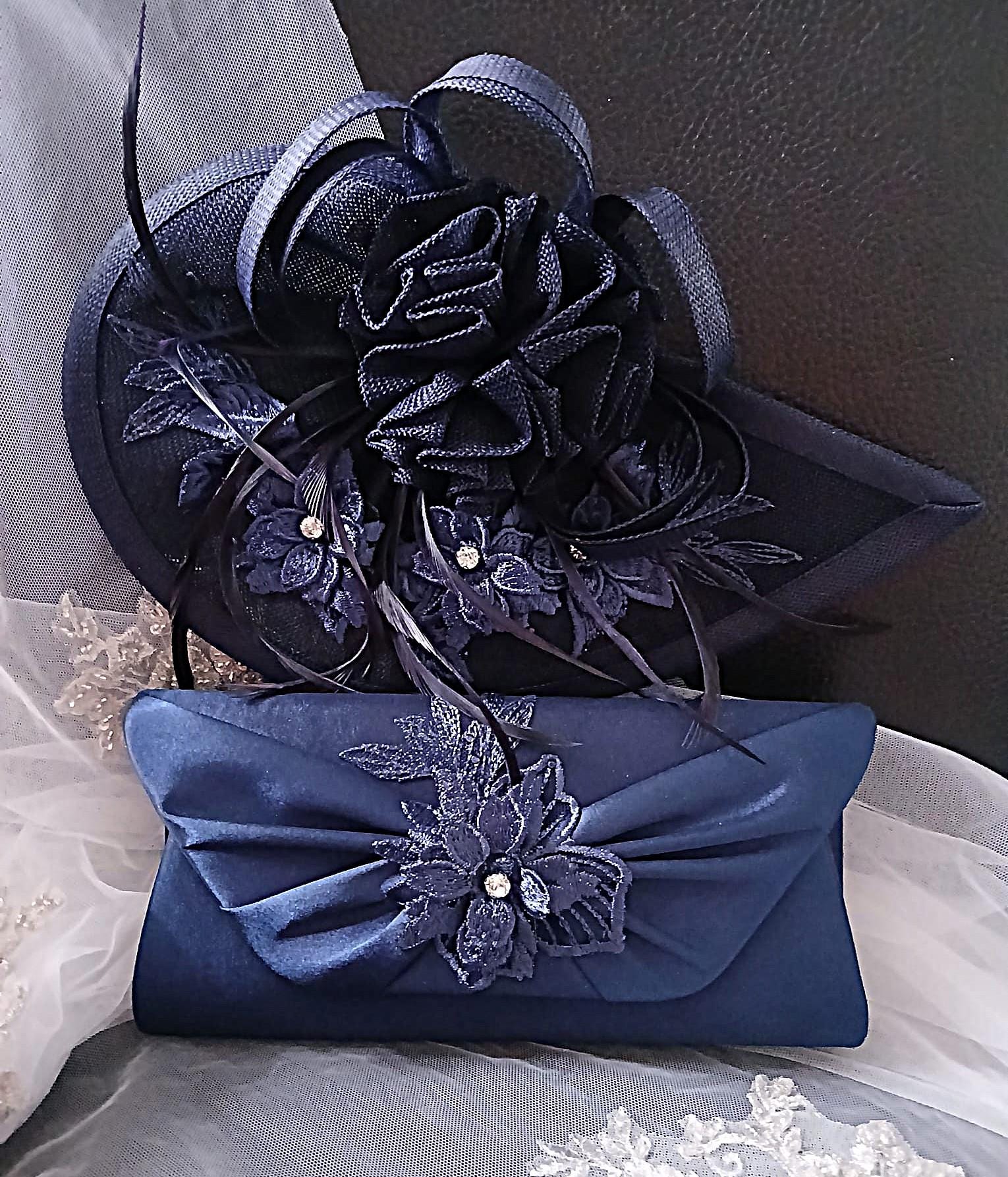 Navy blue fascinator and matching clutch bag on a white lace background